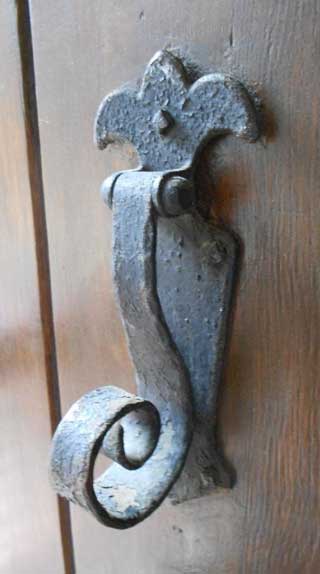 Ornate wrought-iron door knocker on a board-and-batten door at English Village